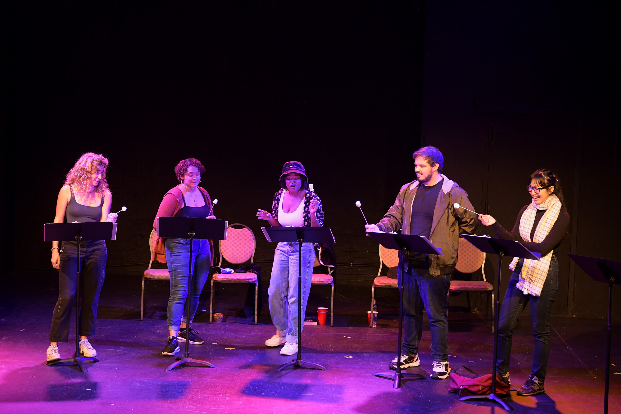 Five actors side by side on stage during a stage reading.