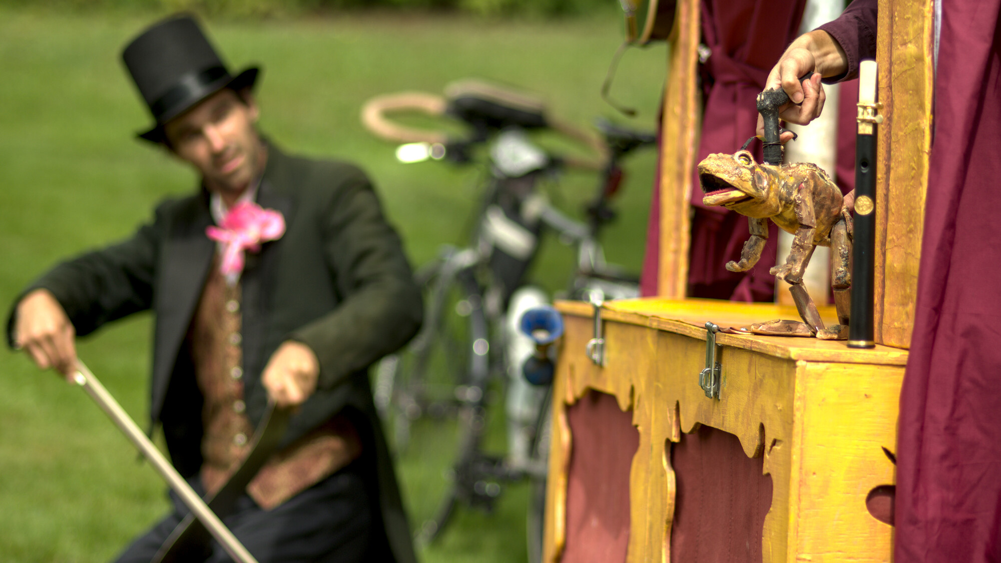 A performer in a top hat with a cane, performing alongside puppets.