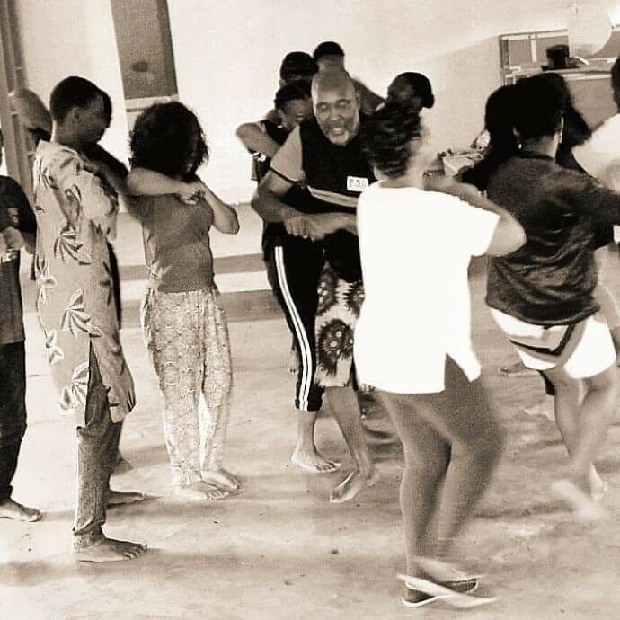 A black and white picture of several people dancing together in a room.
