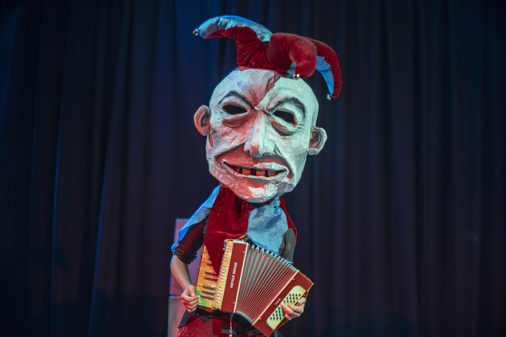 A single puppet with an accordion, staring straight ahead.