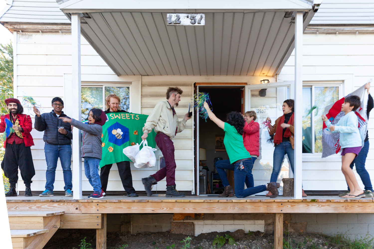 A group of people stand together on the porch of a house.