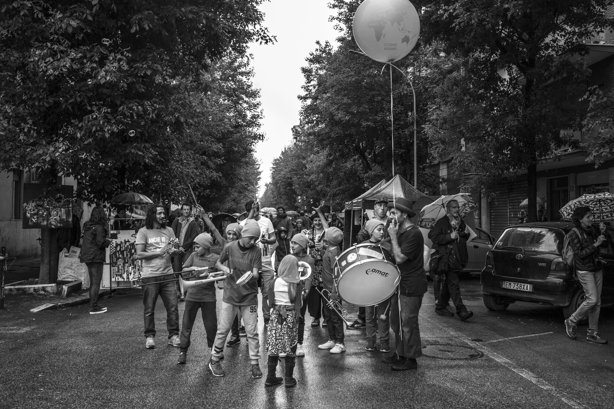 A marching band of adults and children in the street.