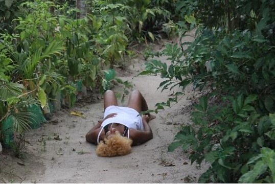 A person lying on their back in the middle of a forest.