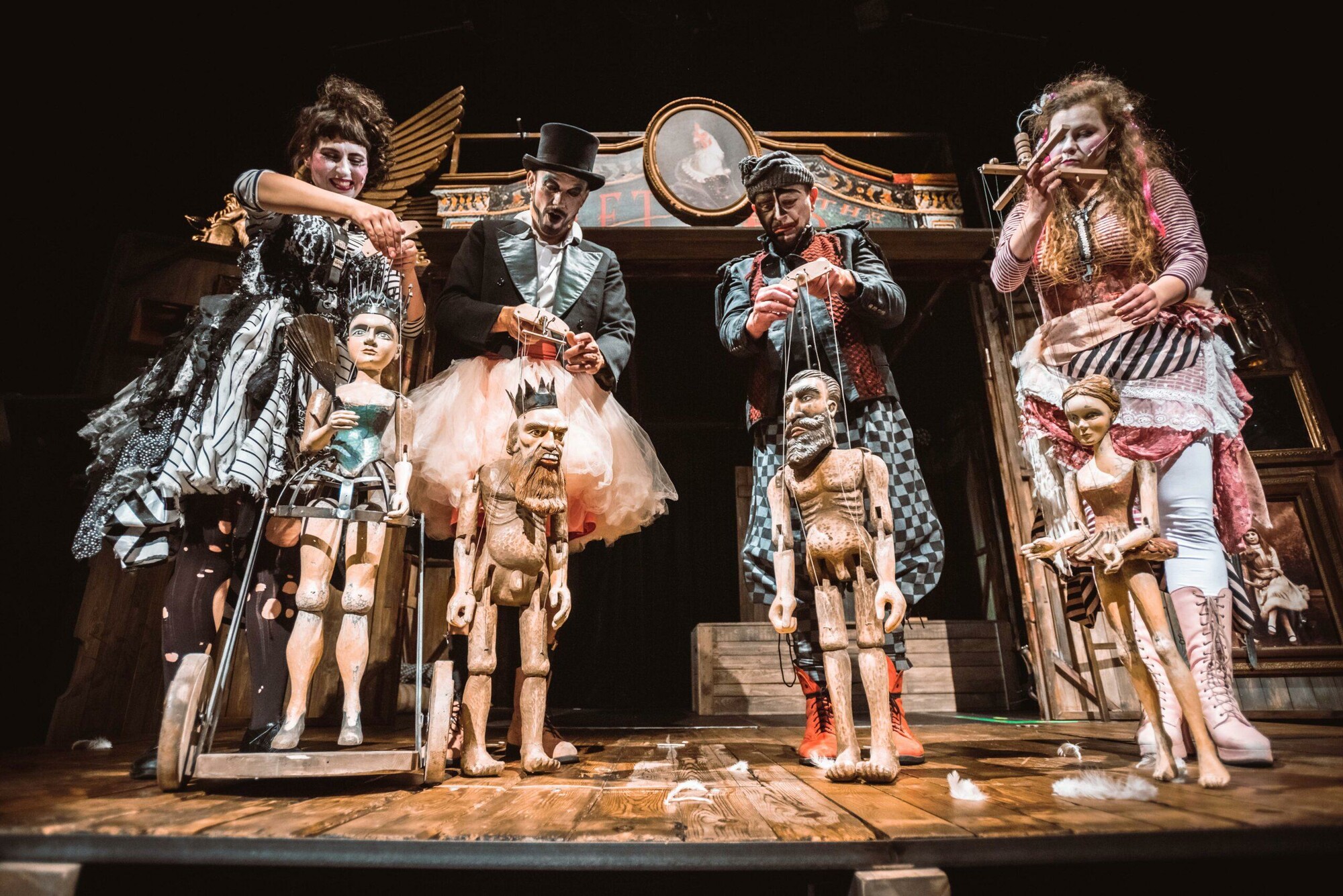Four actors in full costume controlling puppets on stage.