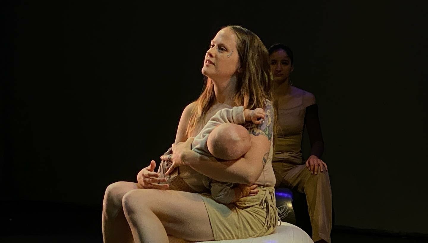 A woman holds a baby in her arms on stage.