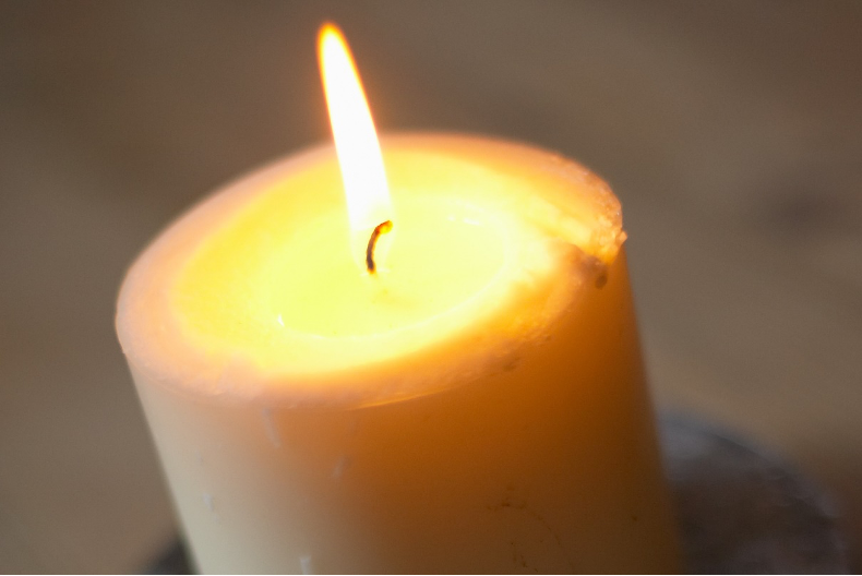 A flame flickers from a wide candle.