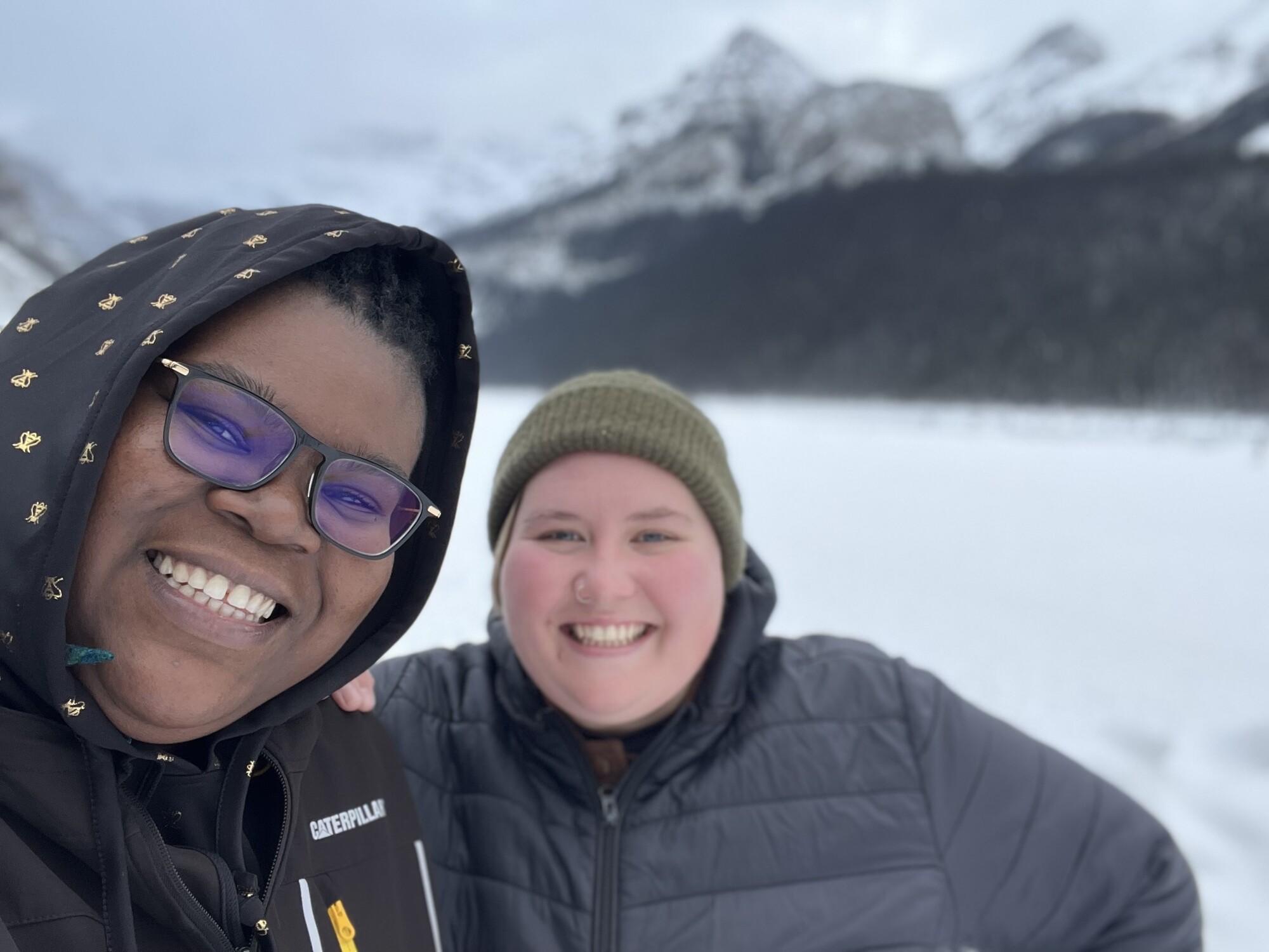 Two people outside on a snowy winter hike smile for a selfie.