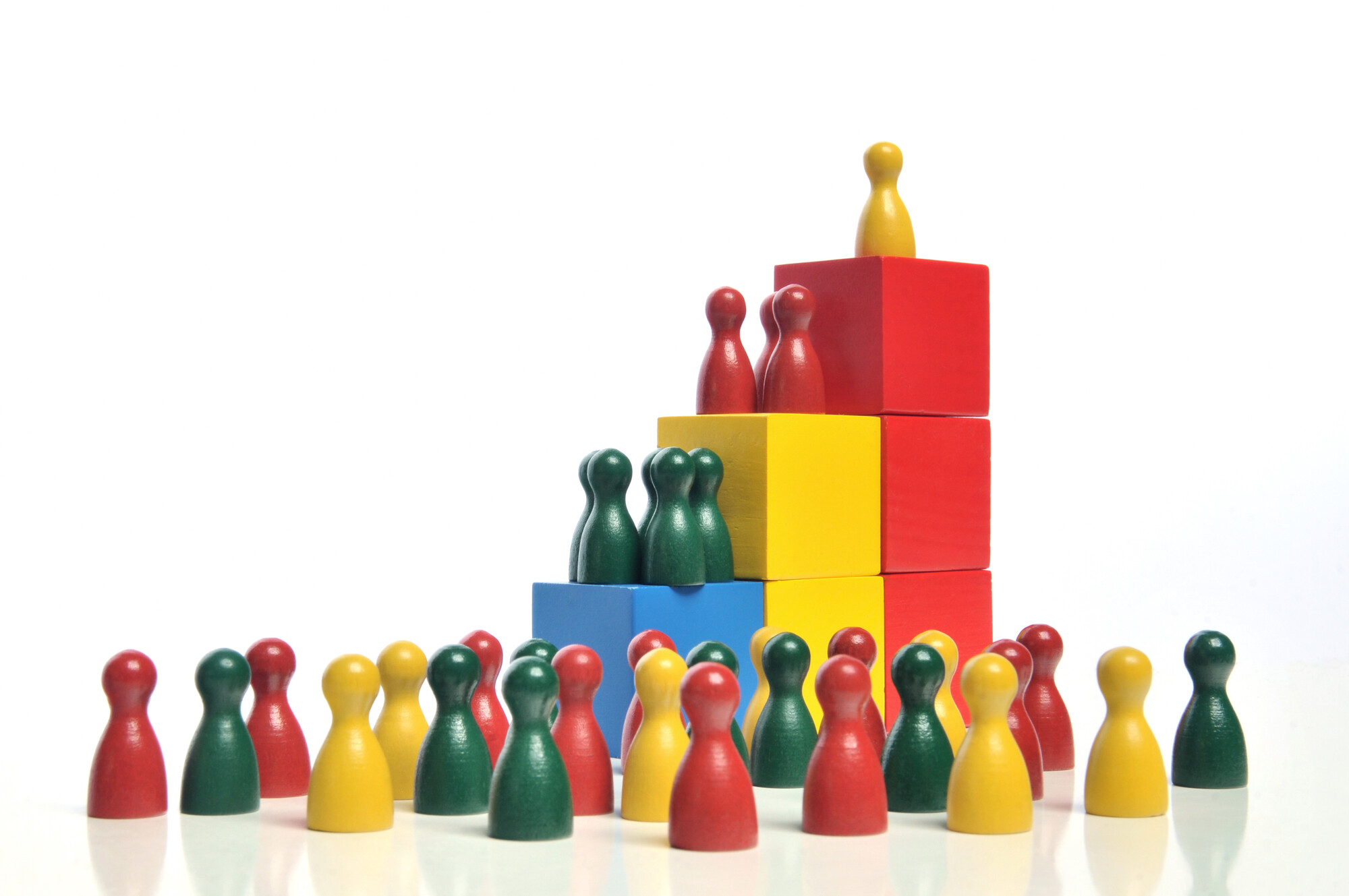 A group of multi-colored pawns facing three increasingly tall stacks of blocks with smaller groups of pawns on each.
