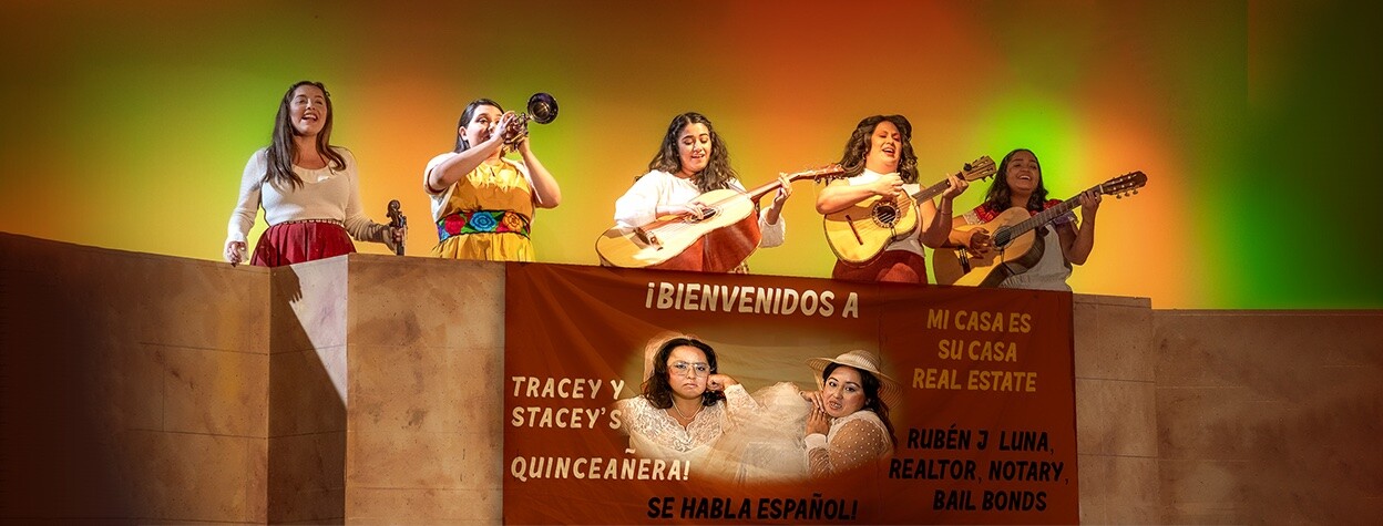 Five women playing instruments on stage, standing over a banner for a Quinceañera.