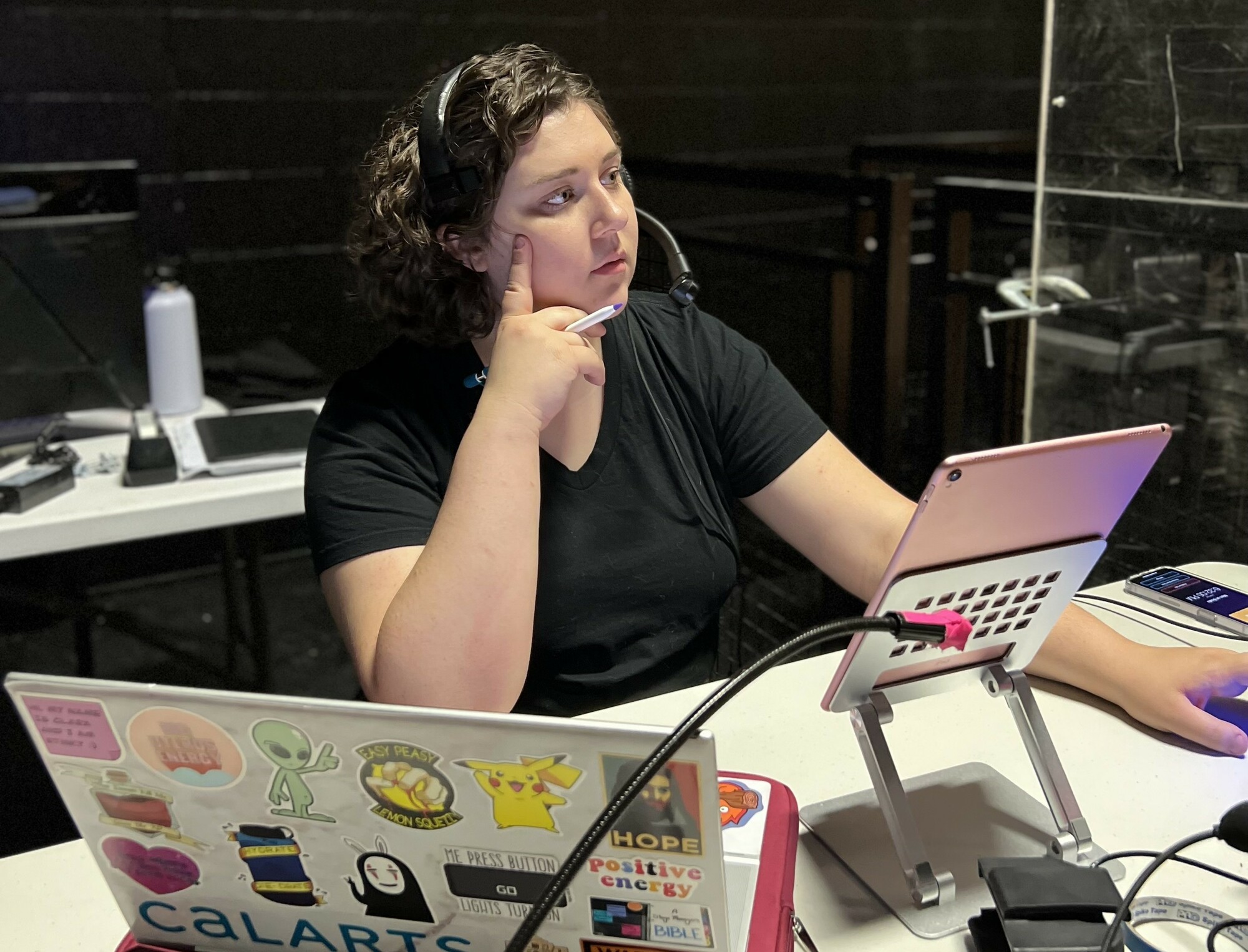 Macy Kunke wears a headset and attends to multiple screens at a stage management table.