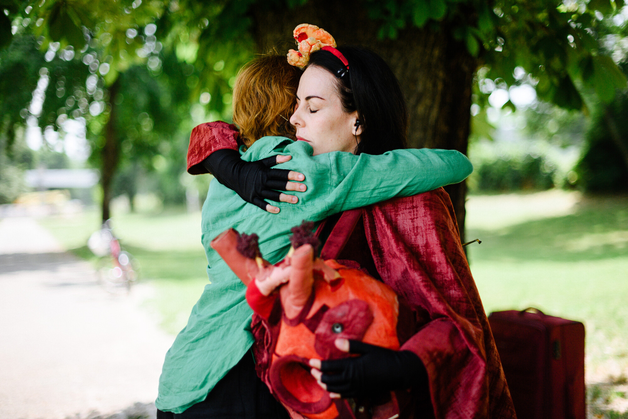 Two women hugging in front of a tree.