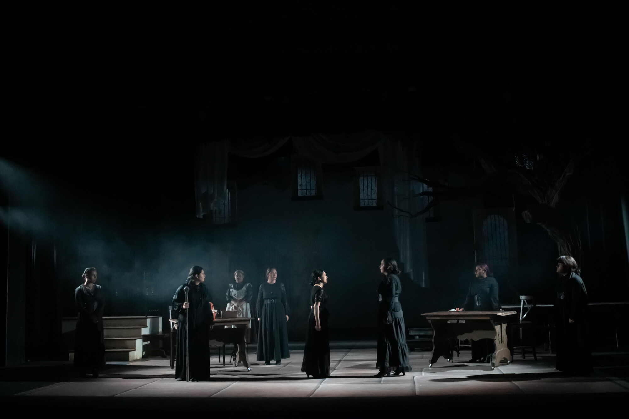 A group of dimly lit figures wearing black onstage.