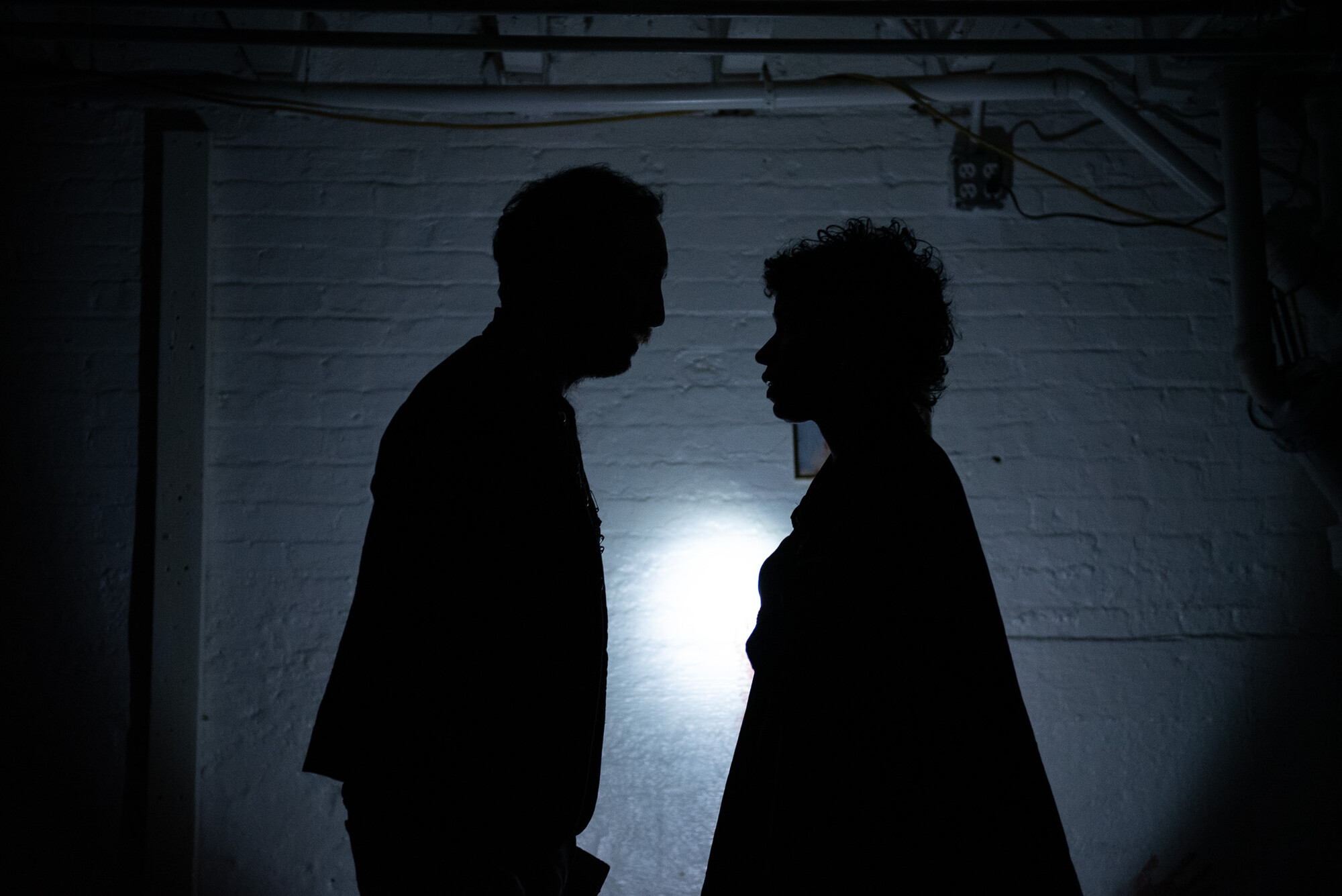 Two actors stand in silhouette. 