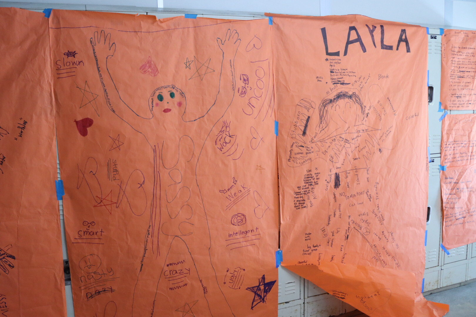 Large outlines of children drawn onto brown paper.