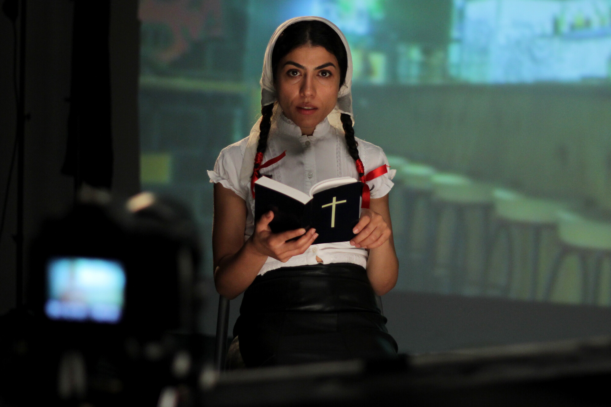 A woman reads from a bible onstage.