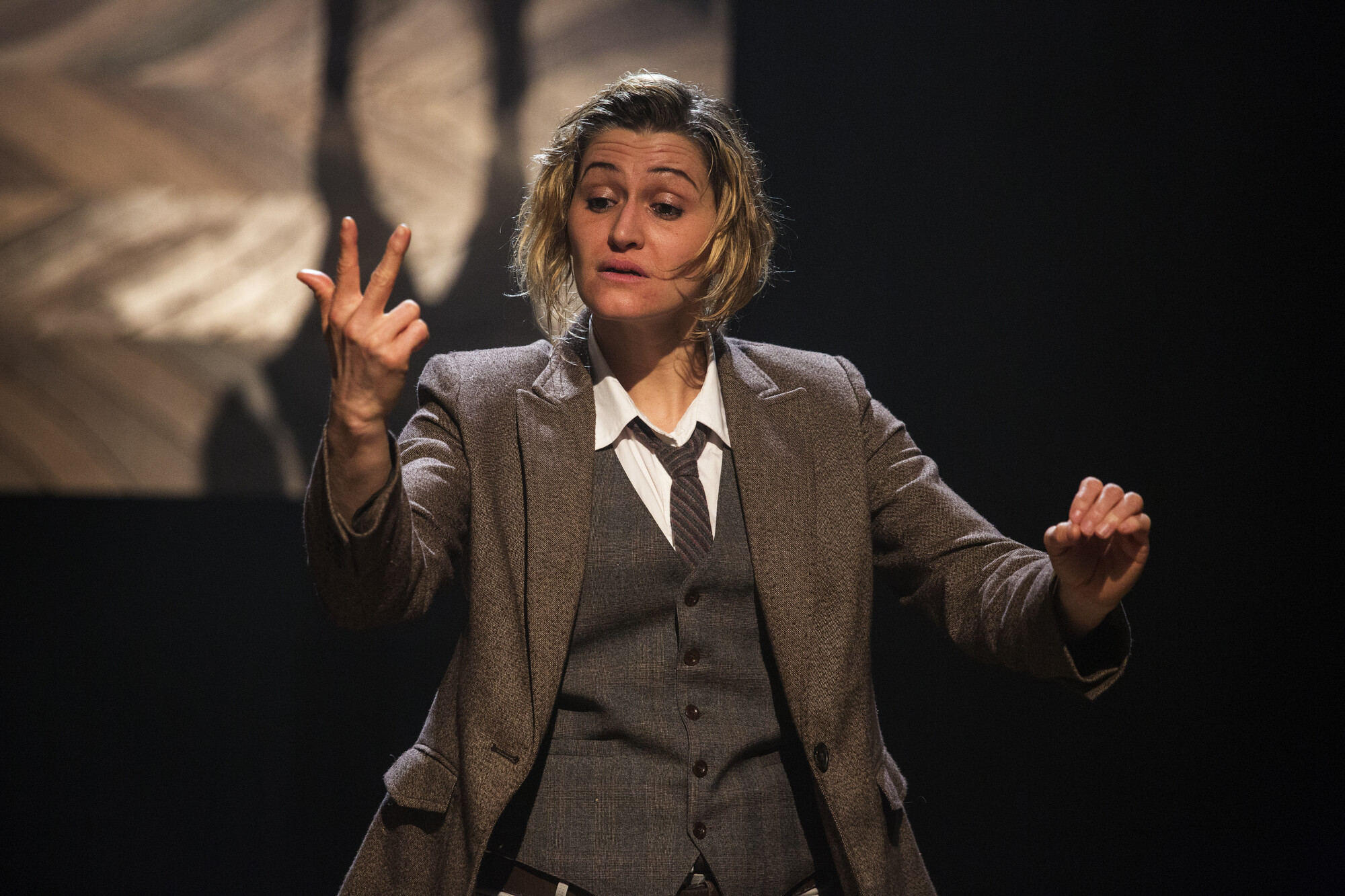 An actress in a suit performs onstage.
