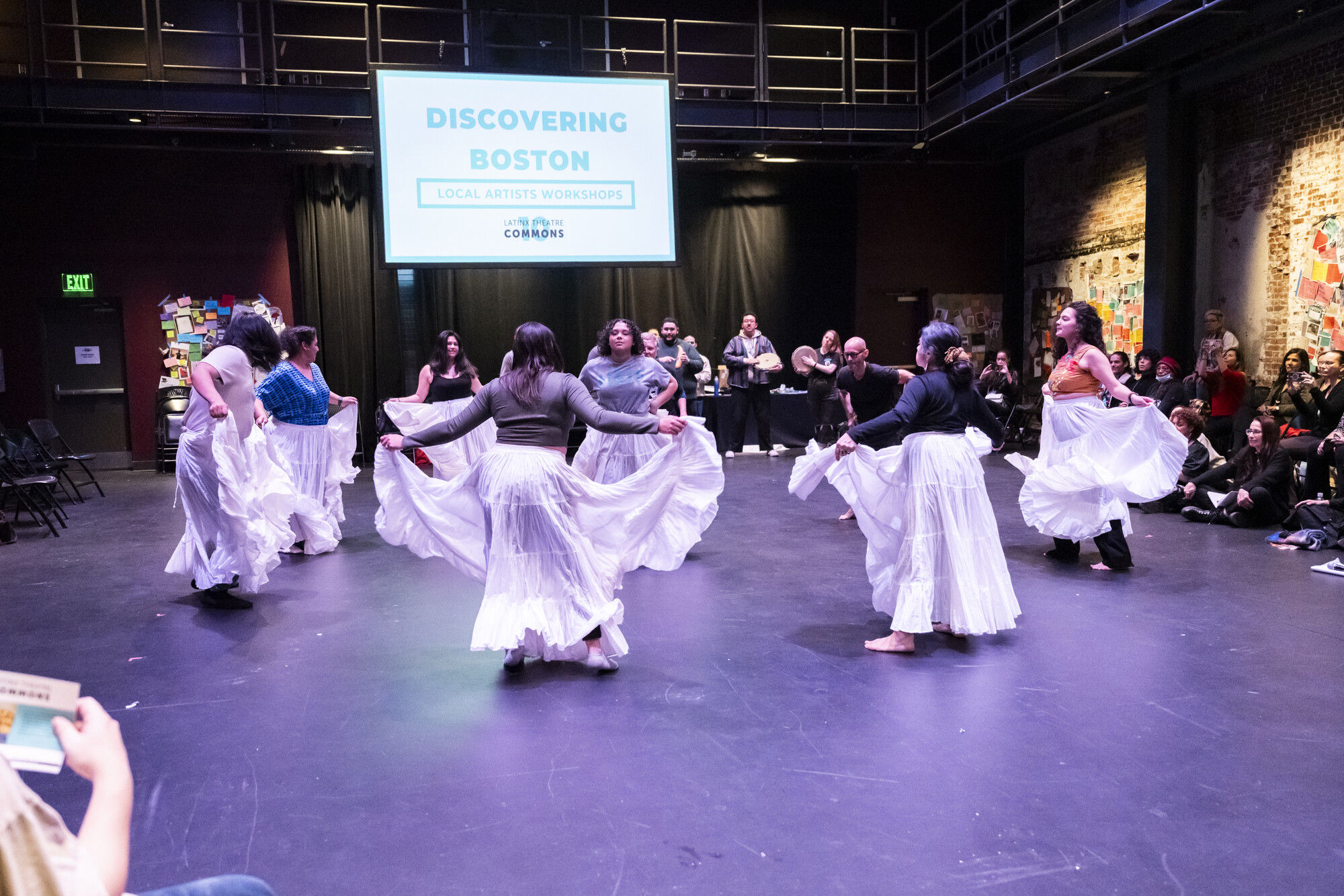 Participants in white skirts dance in a circle.