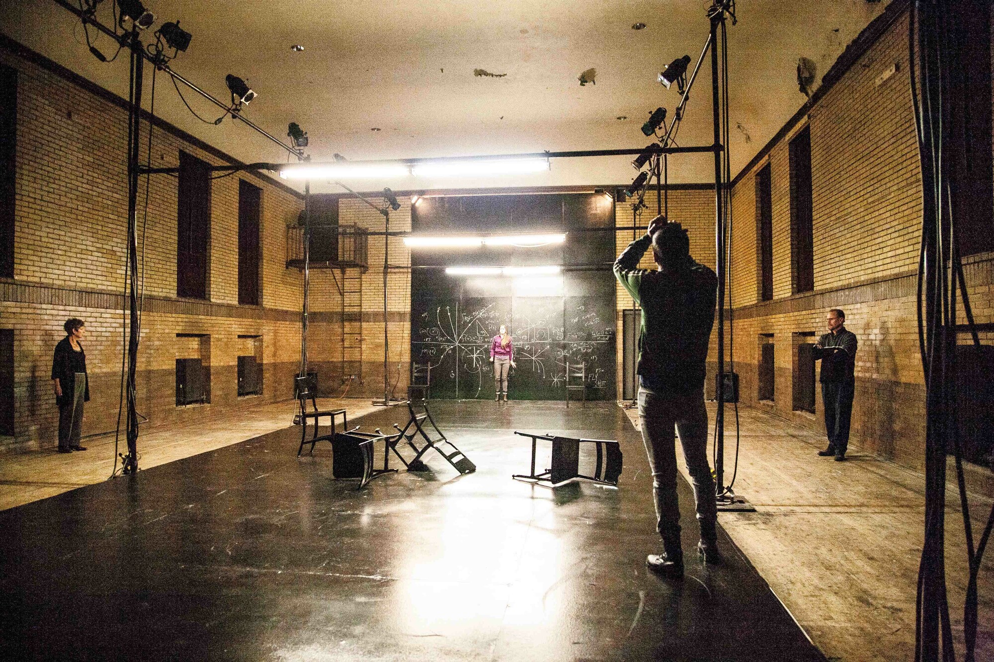 Artists work in an a bare studio space with chairs on the floor.