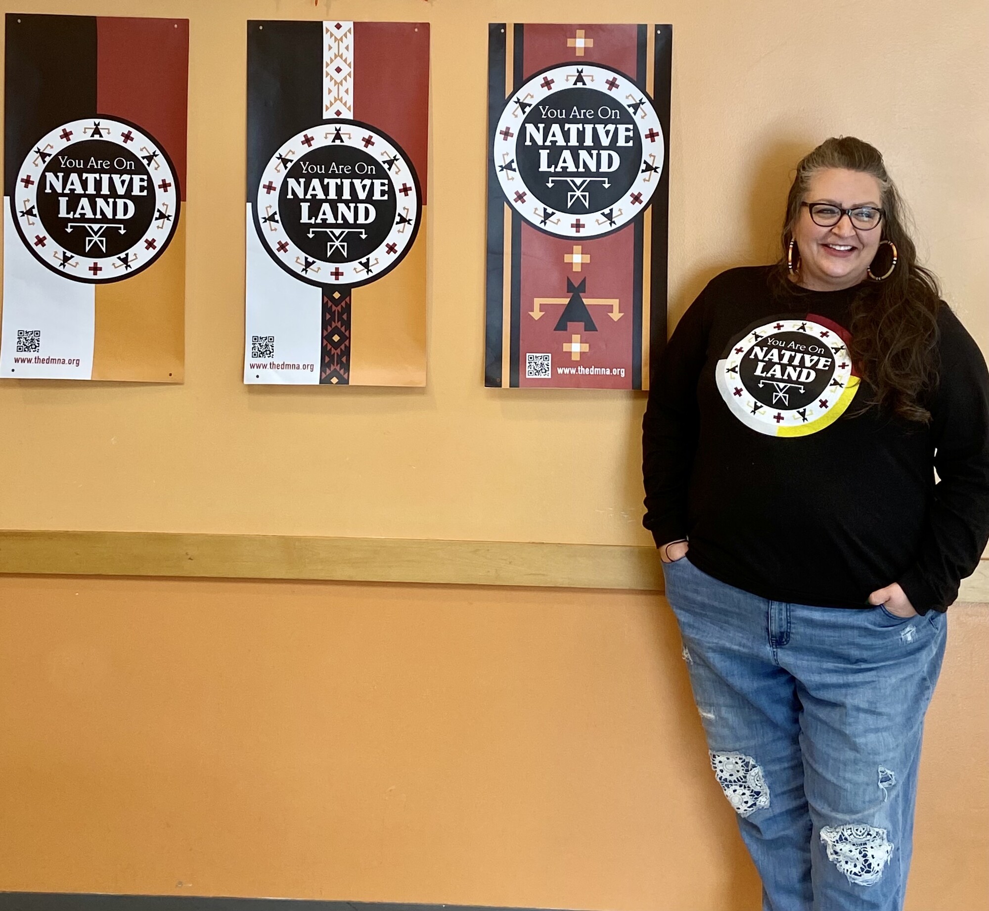 A woman standing next to banners reading You Are On Native Land.