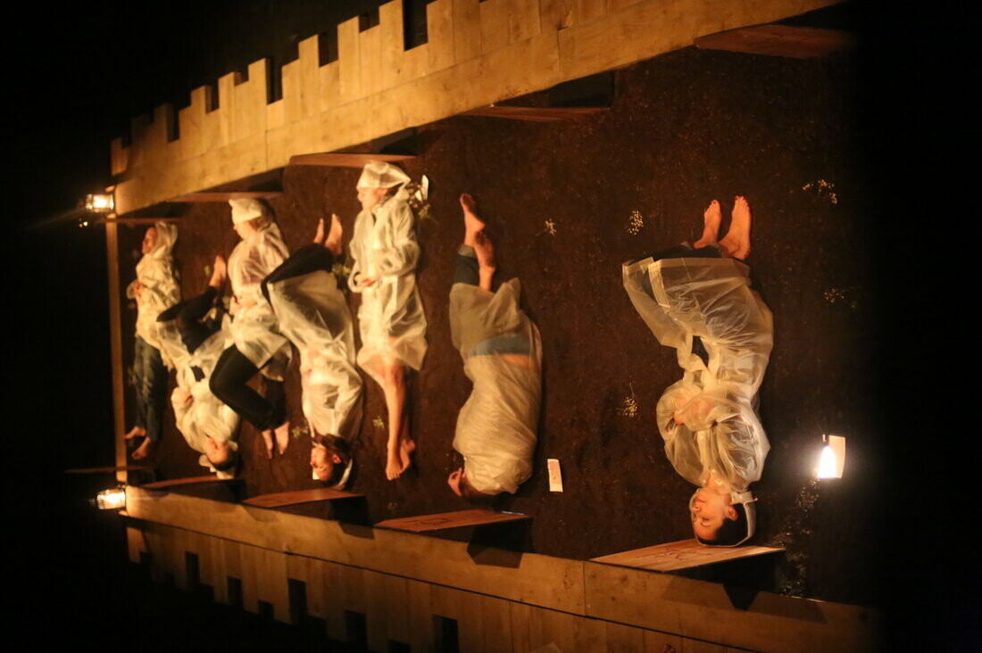 A row of people lie on the ground in a performance piece.