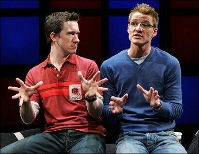 Two actors engage in a discussion on stage. 