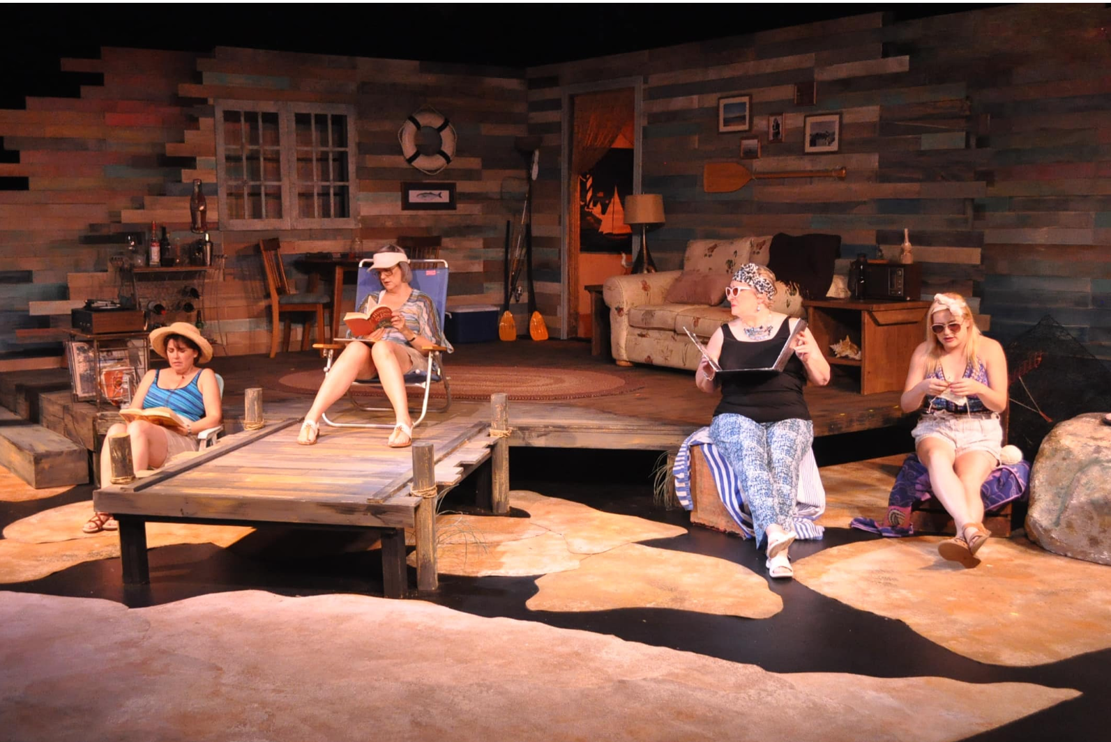 A group of people lounge on stage in beachwear.