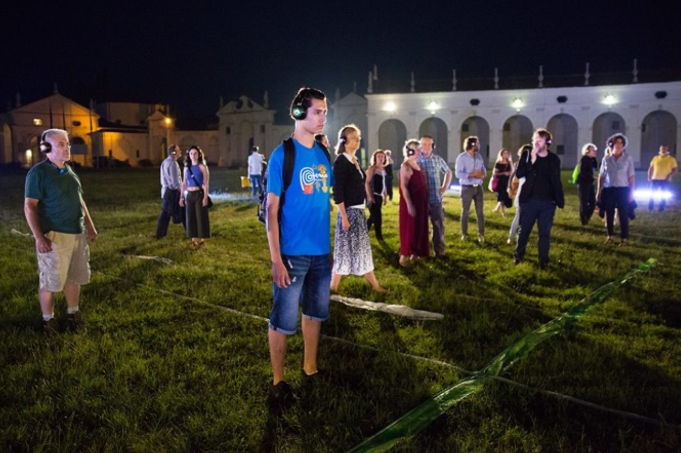 A group of people standing outside at night with headphones on.
