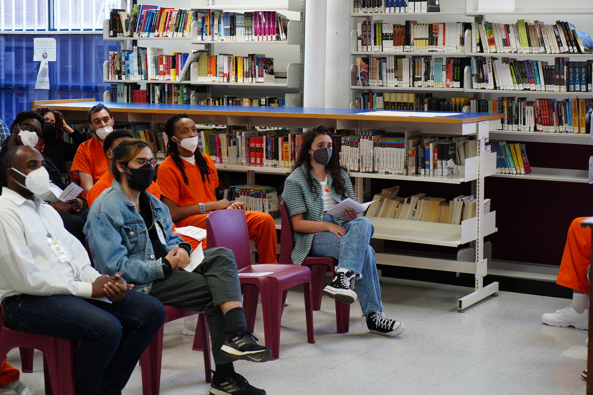 audience members wearing masks sit in a library for a Spit Dat presentation.