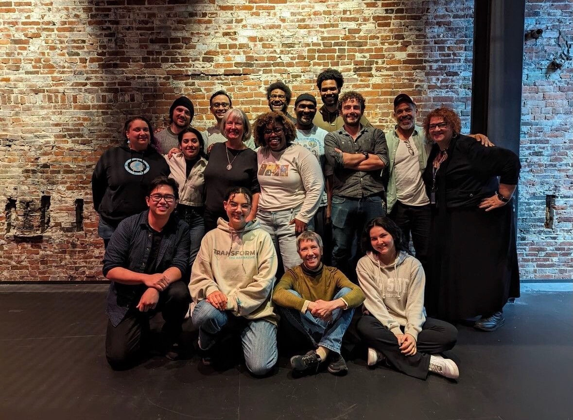 A candid photo of a group of people standing in front of a brick wall.