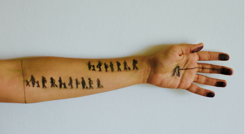 An arm with a tattoo of people standing in a row. 