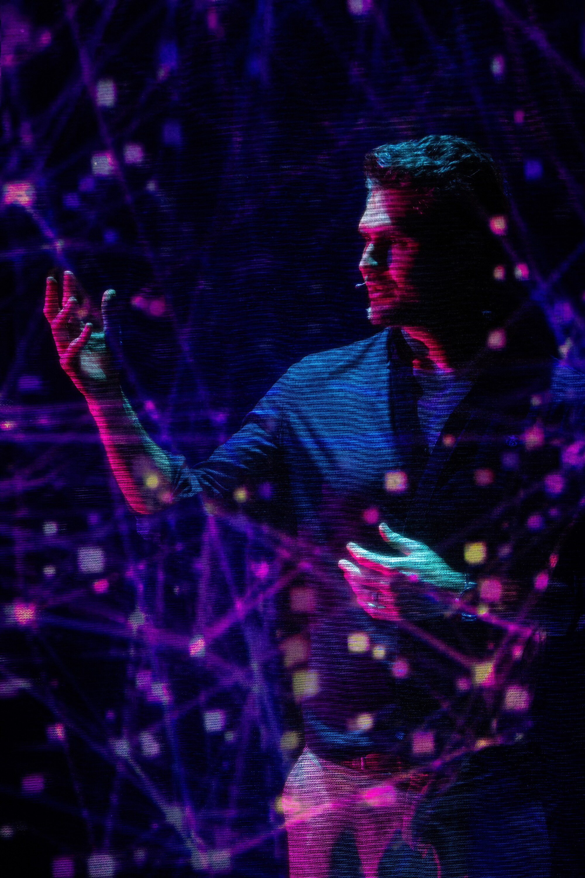 A man looking introspectively at his hand in tech inspired neon light. 