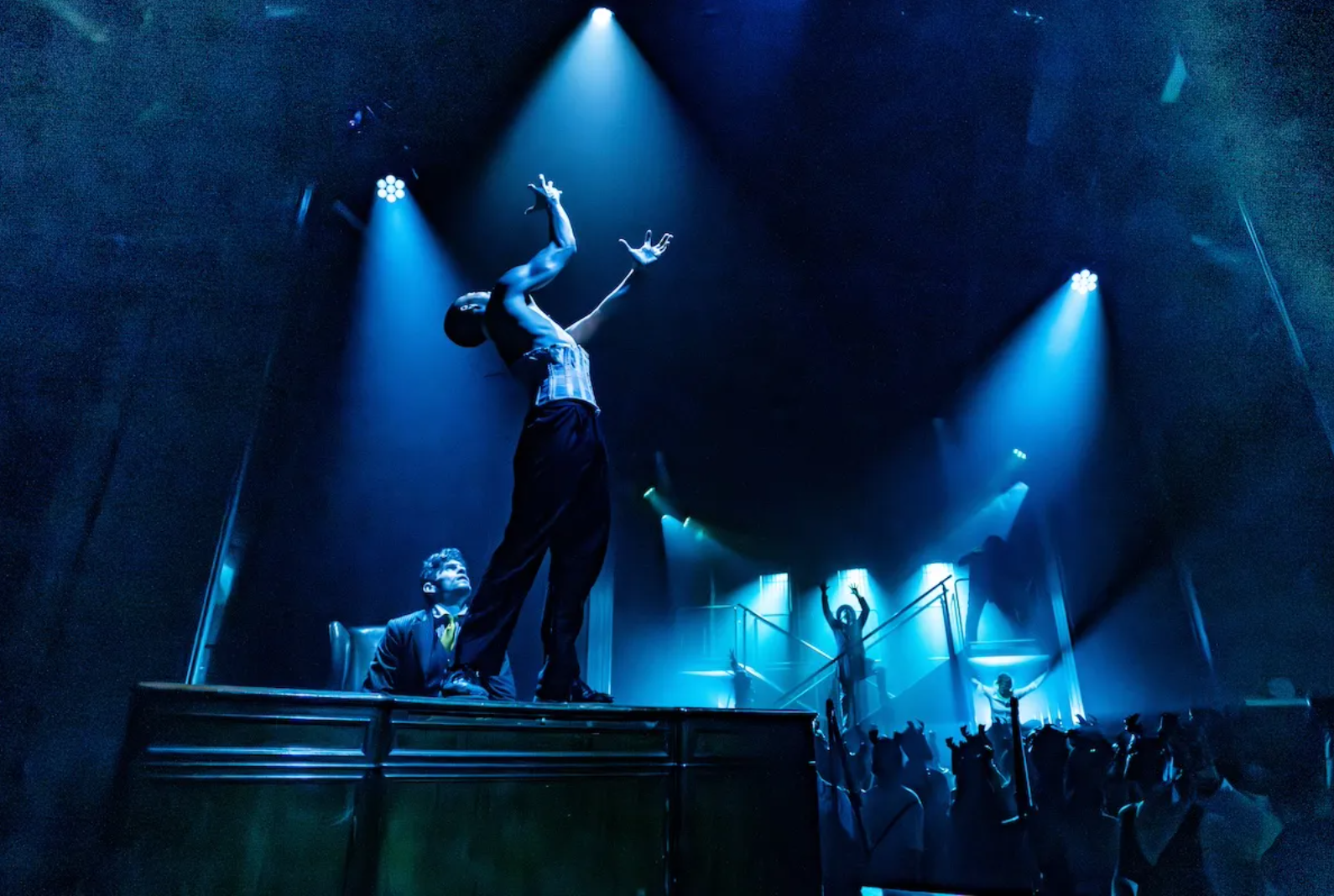 A person reaches up passionately on stage. 