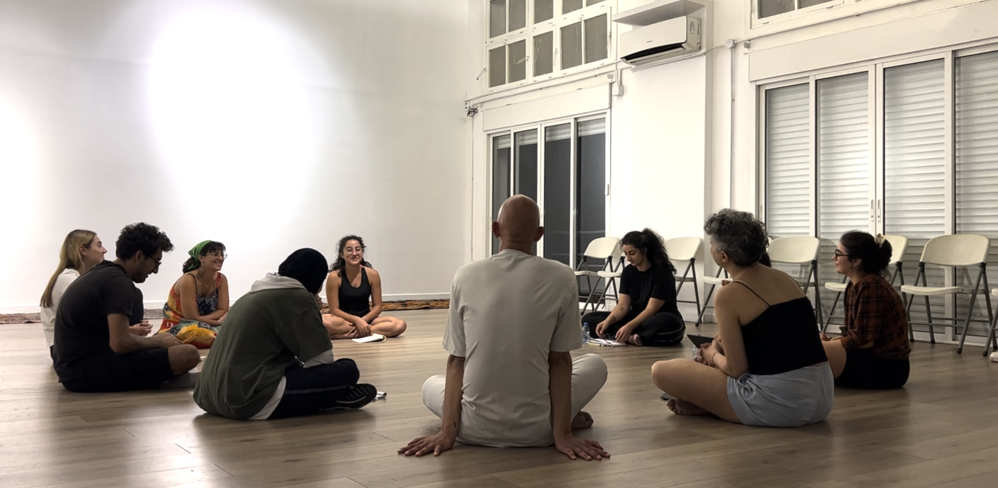 A group of people sit on the floor in a circle.