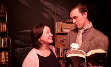 Two people share an excited look while looking in a book. 