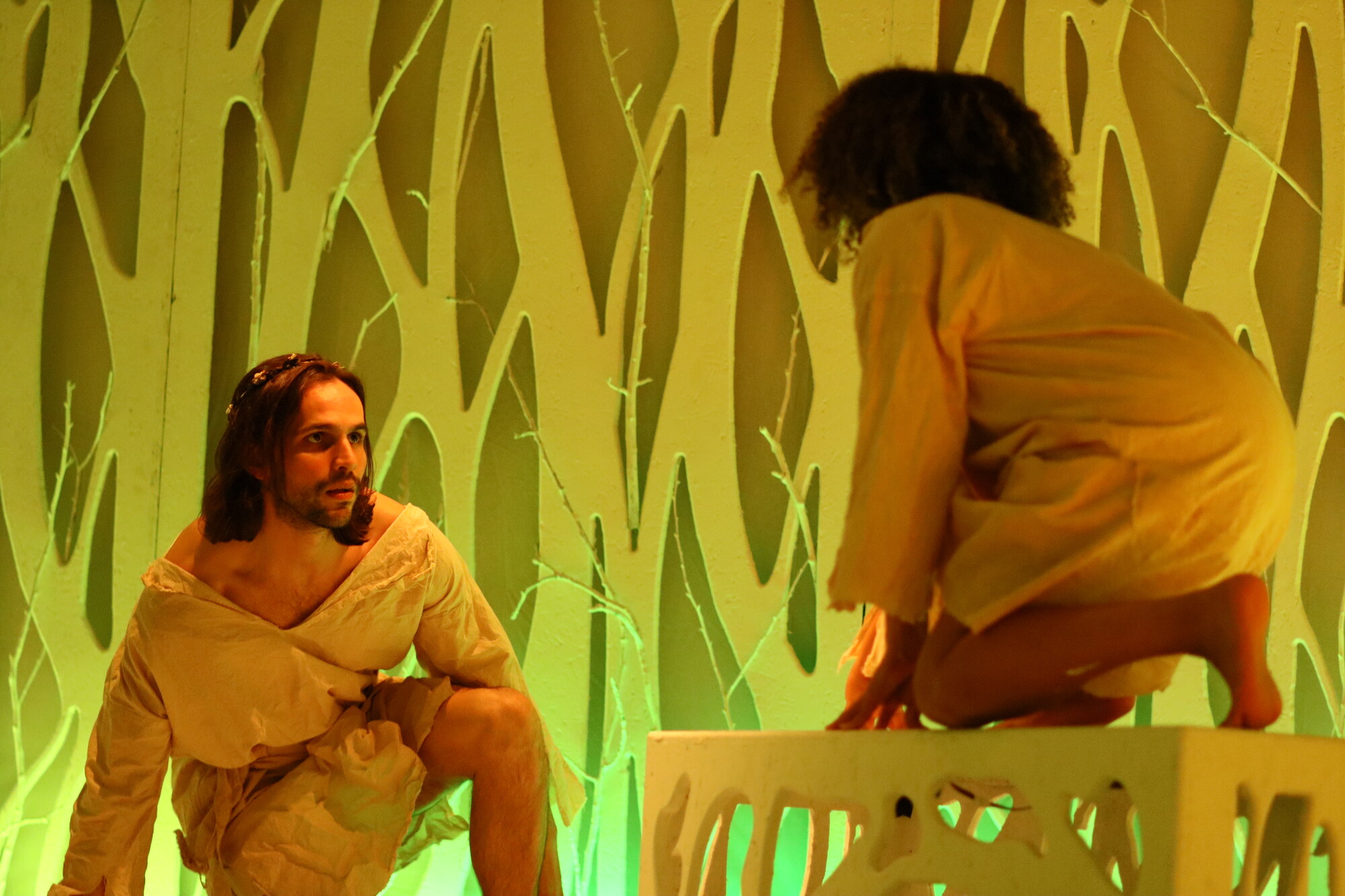 Two people are crouching, one on a table and one on the ground. 