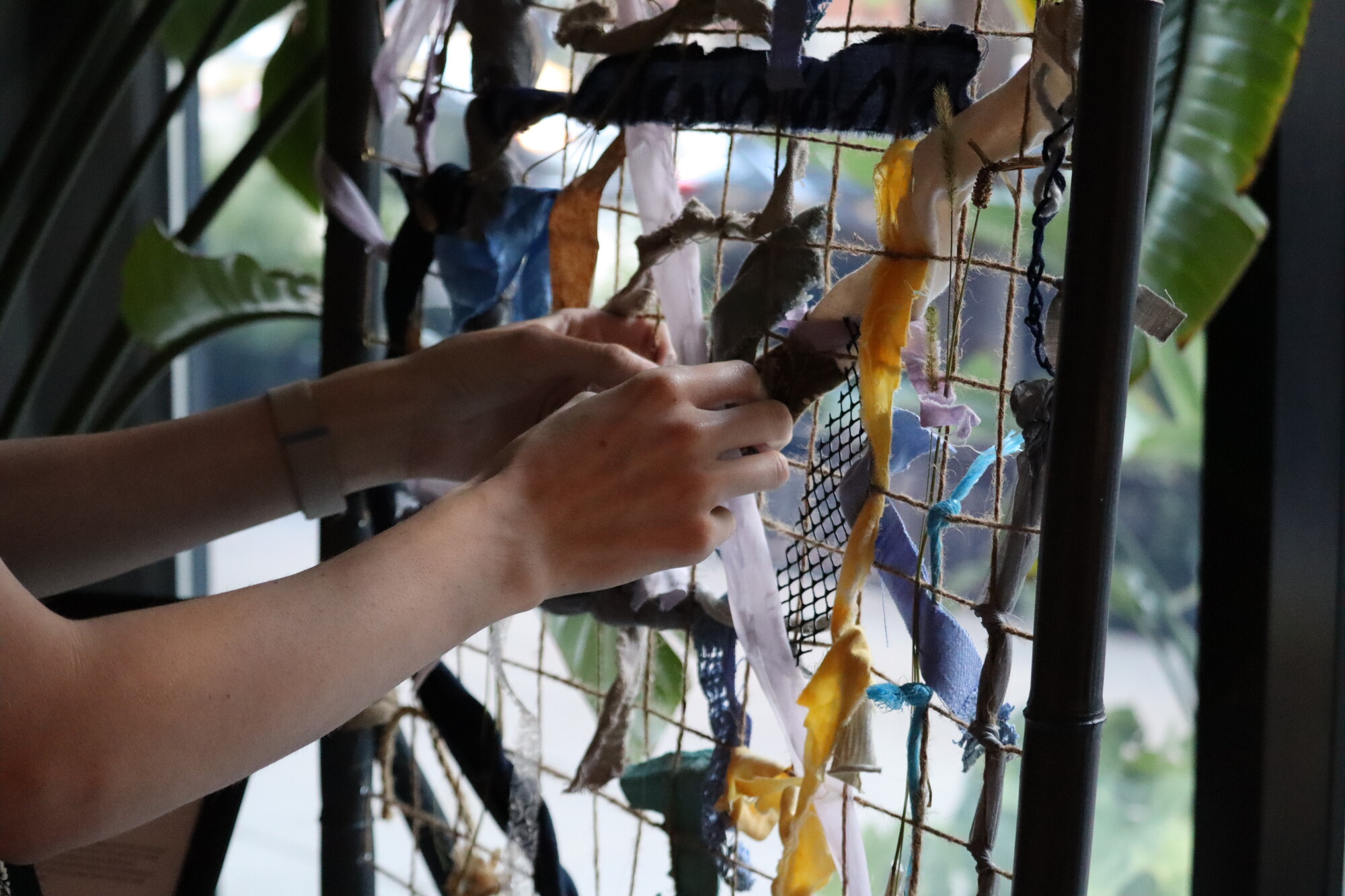 A person's hands working with strips of fabric. 