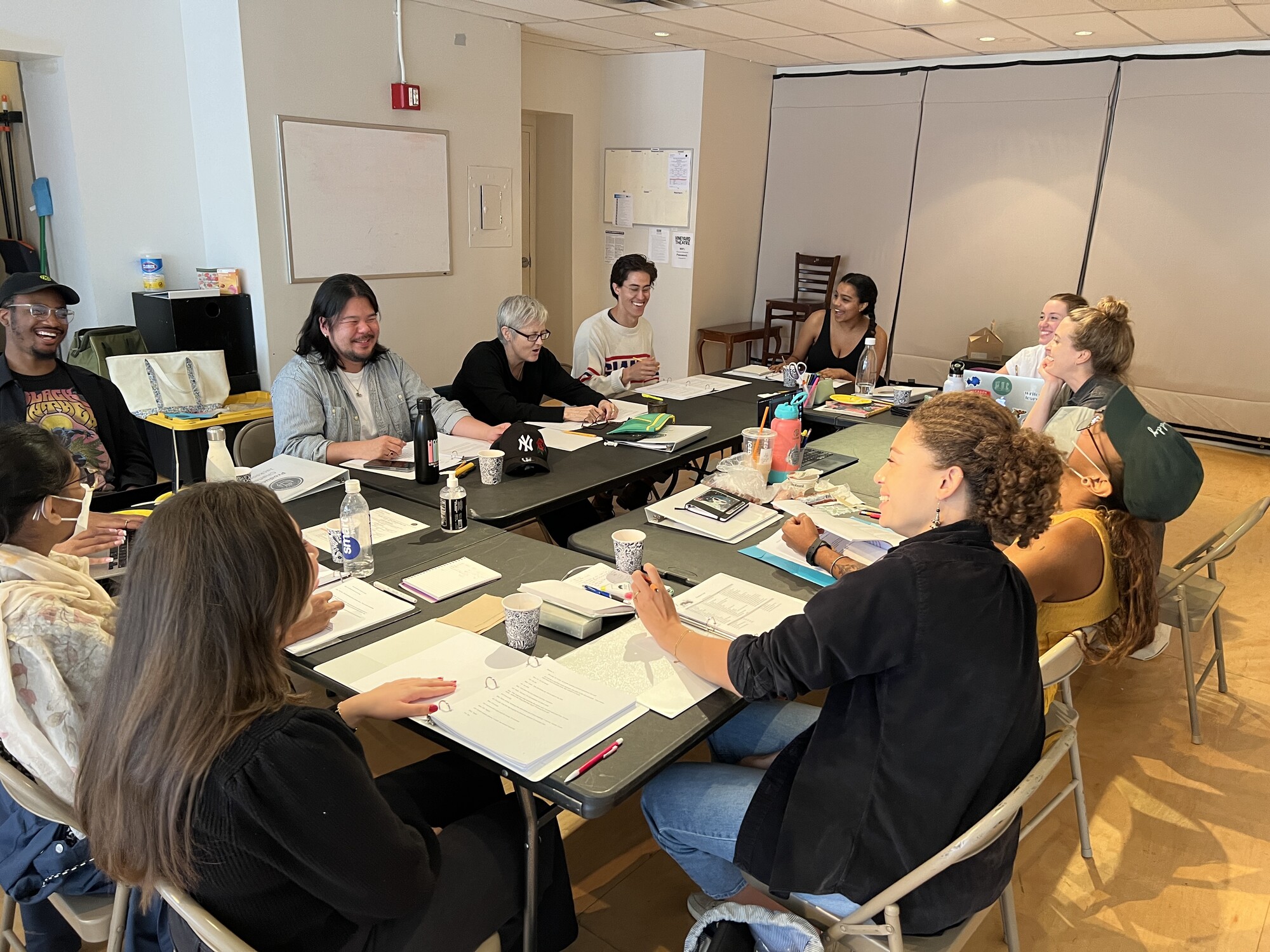 A group of people sitting around a table reading scripts.