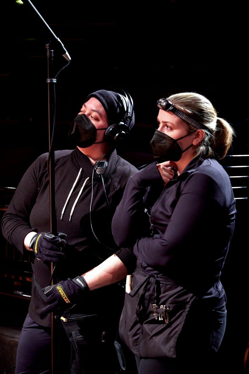 Two people dressed in black working stage equipement. 