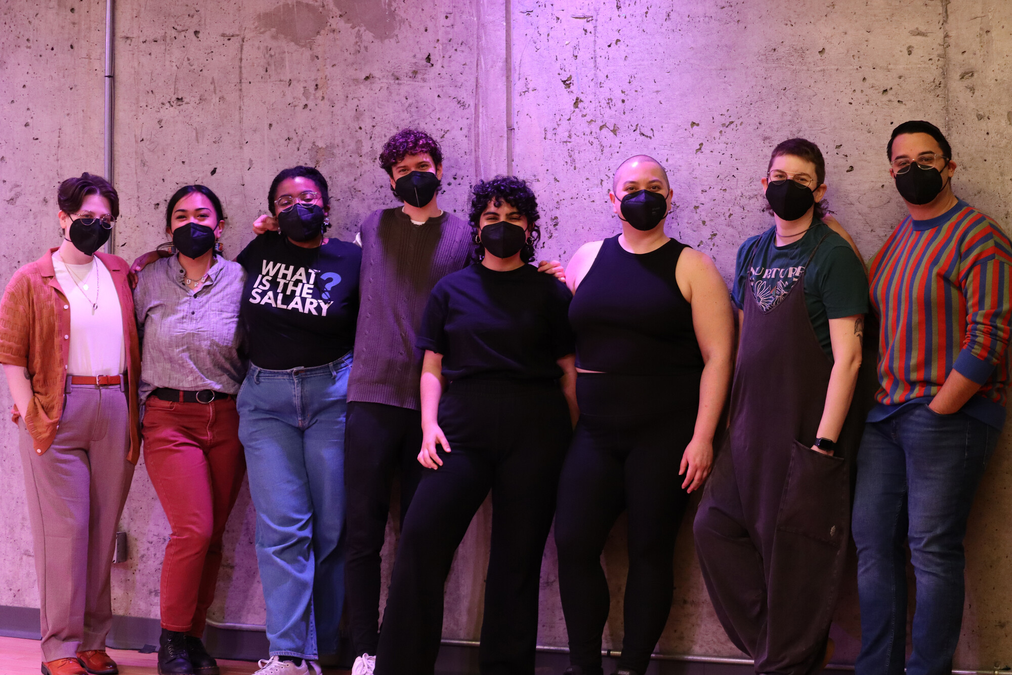 A group of people standing in a line wearing black face masks. 