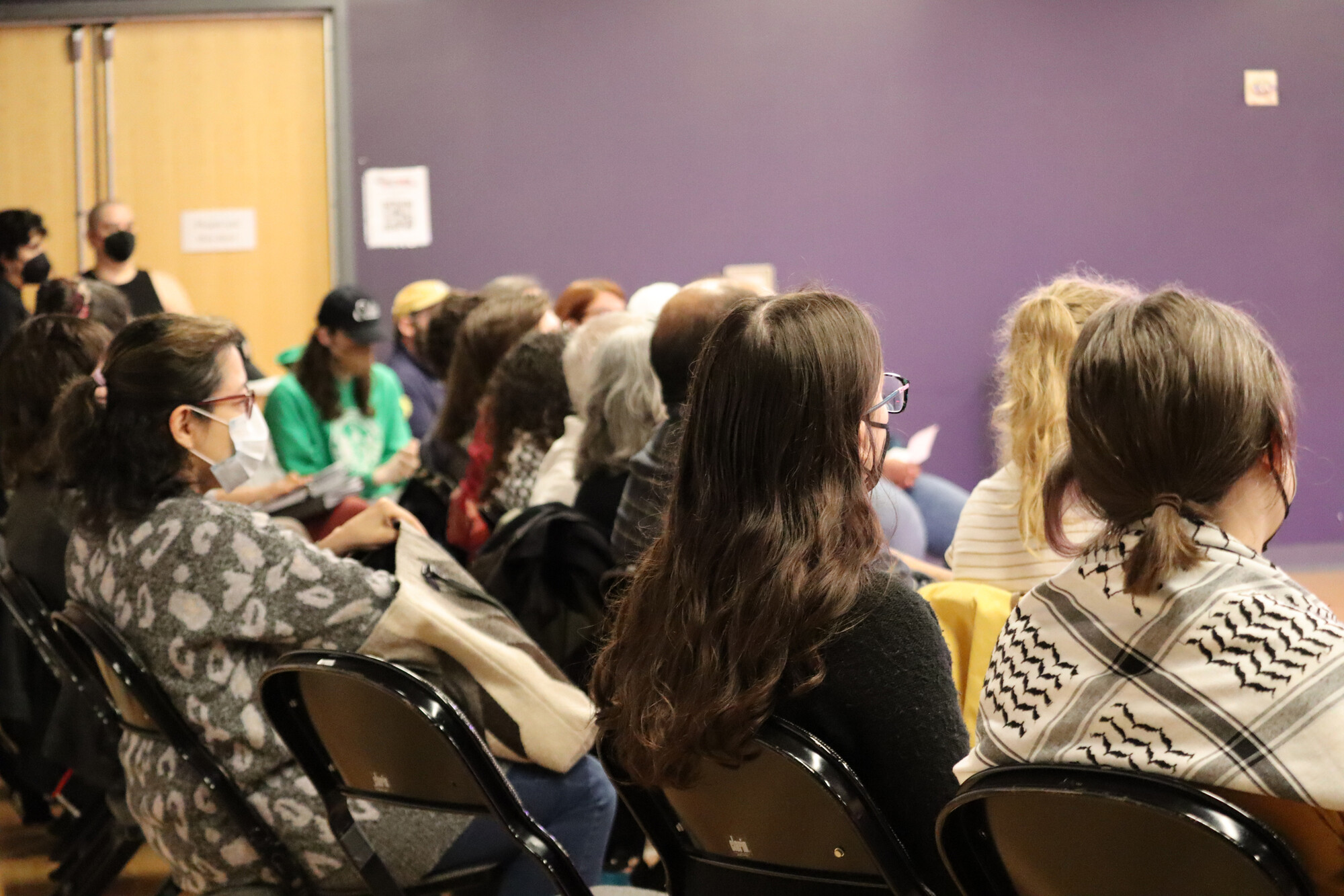 The backs of people's heads as they sit in an audience.