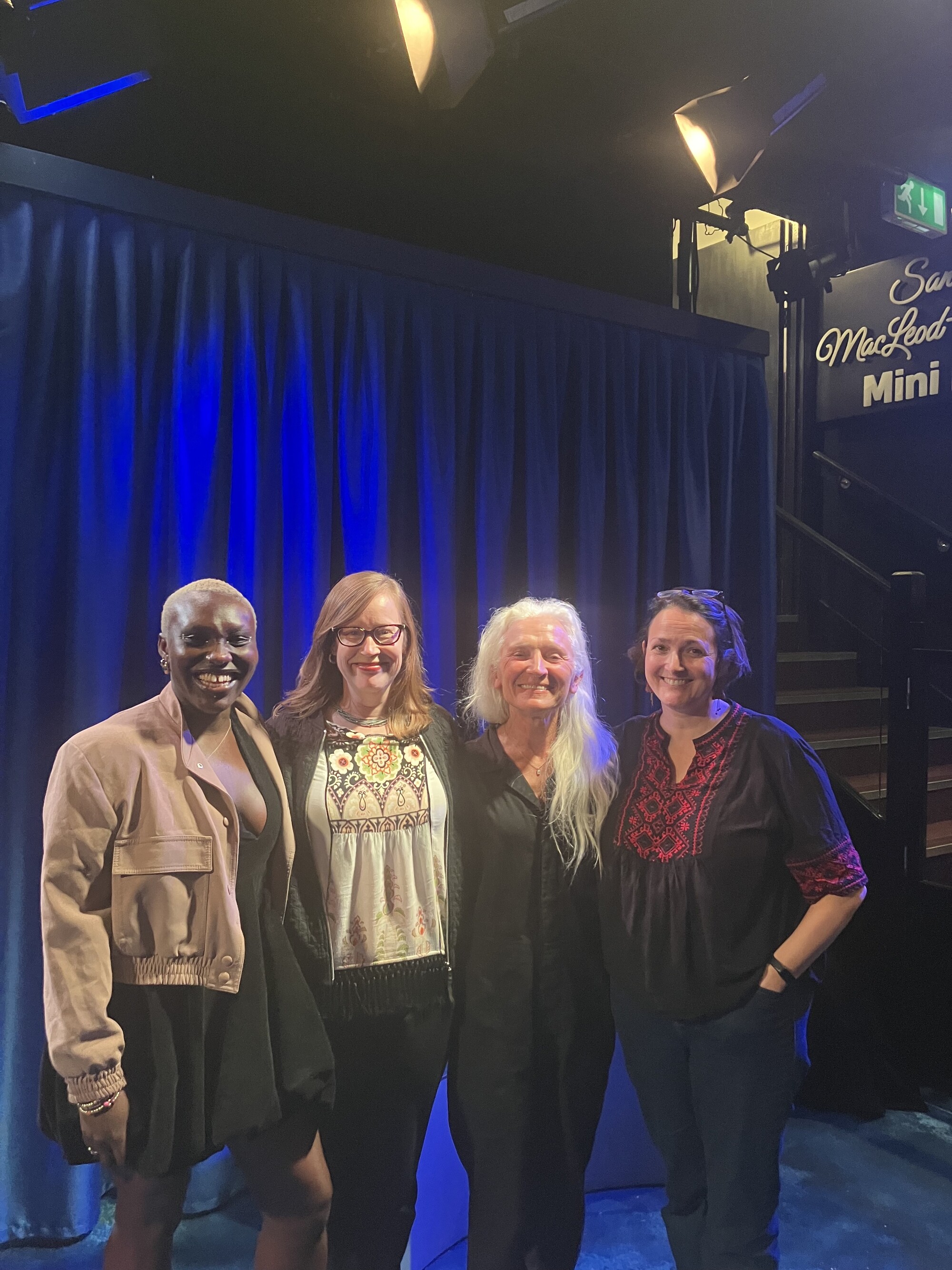 Four smiling women stand together. 