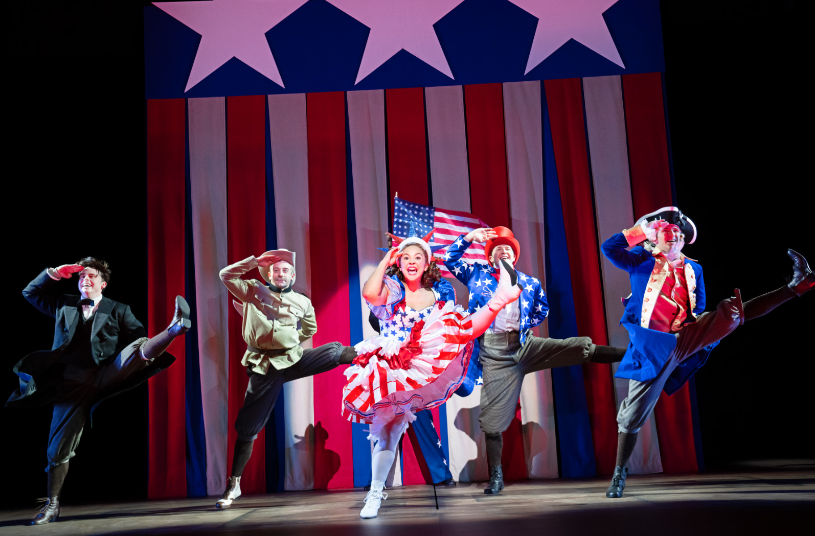 People on stage in patriotic costumes in a choreographed dance. 