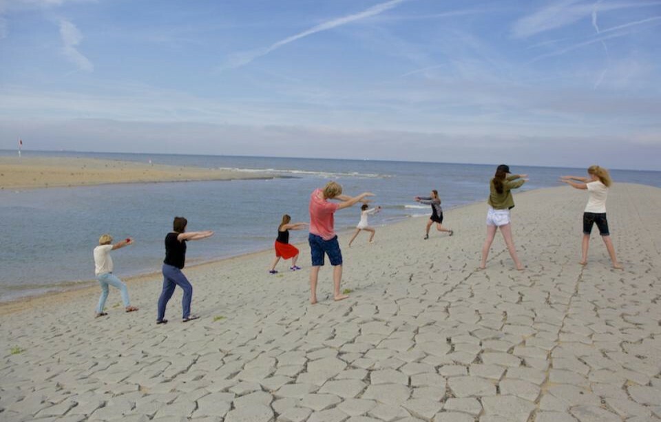 A group of people participating in movement on some rocks near water. 
