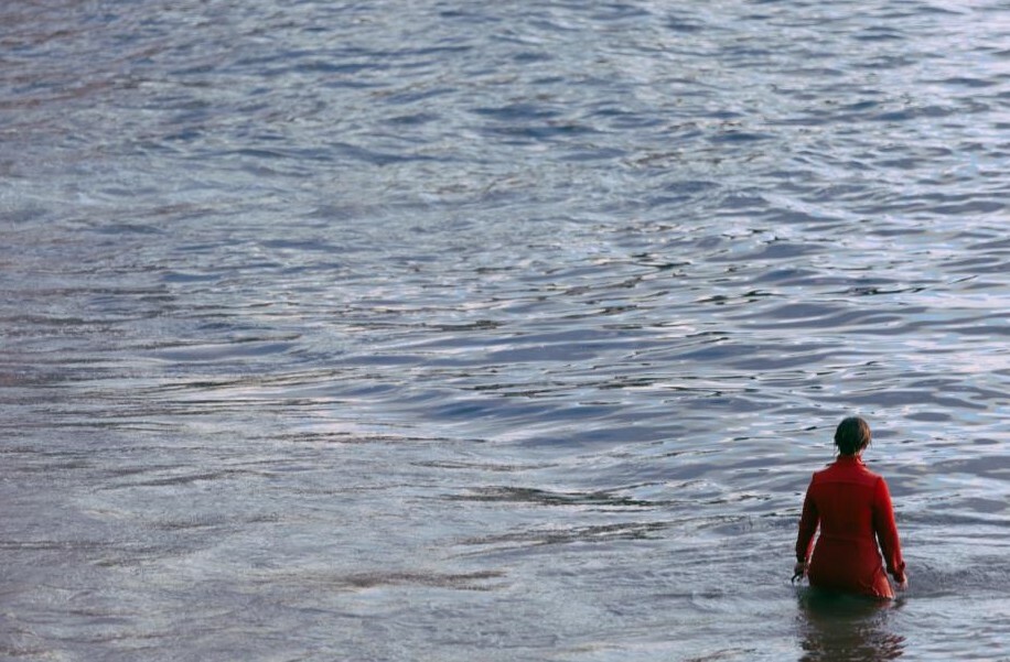 A person dressed in red standing in a body of water. 