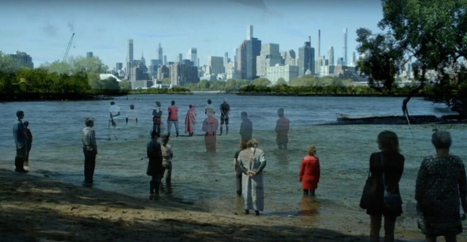 A lot of people standing in shallow water. 