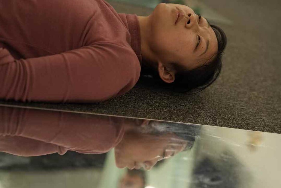 A person laying down next to a mirror.