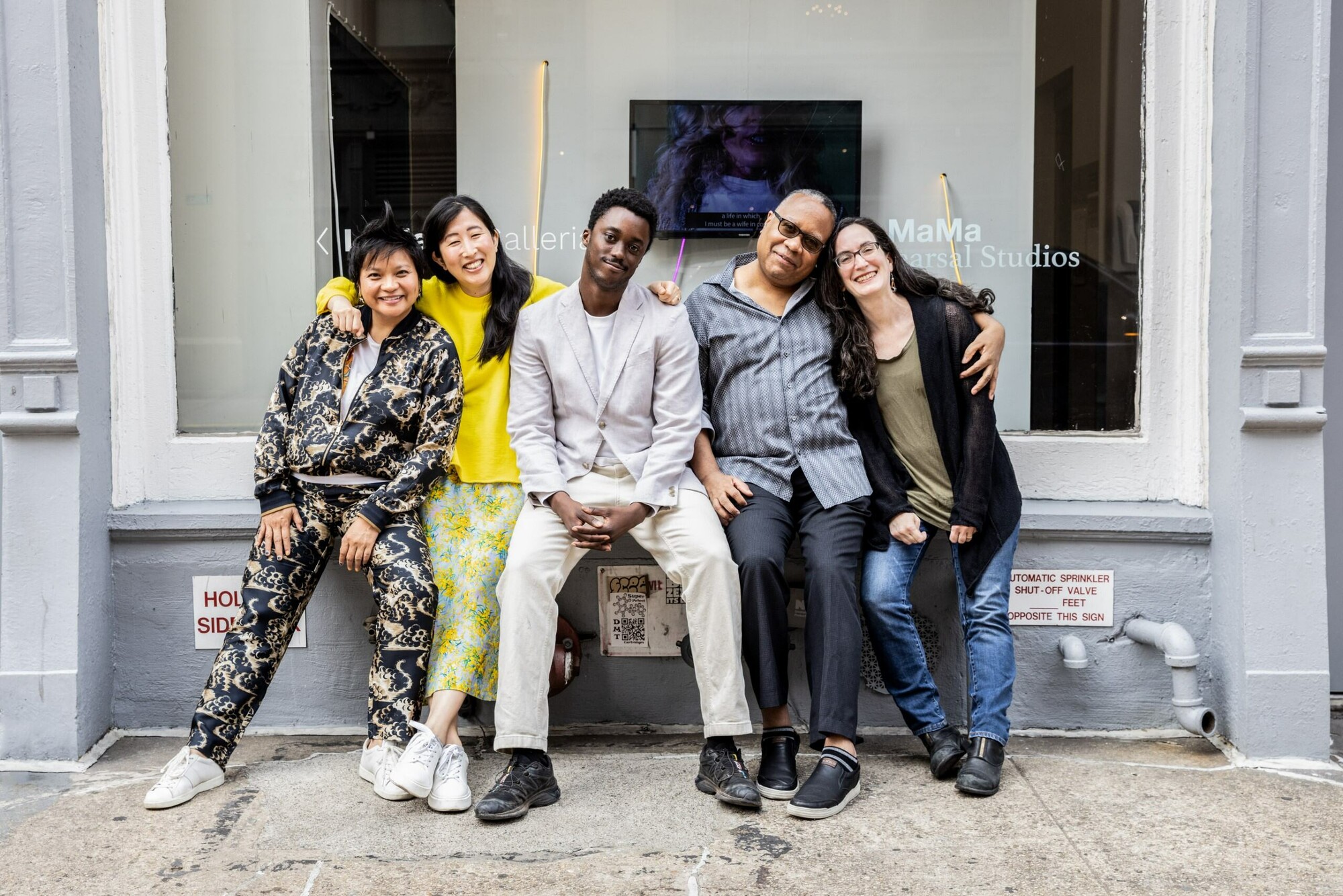 A group of people sitting together outside a city building. 