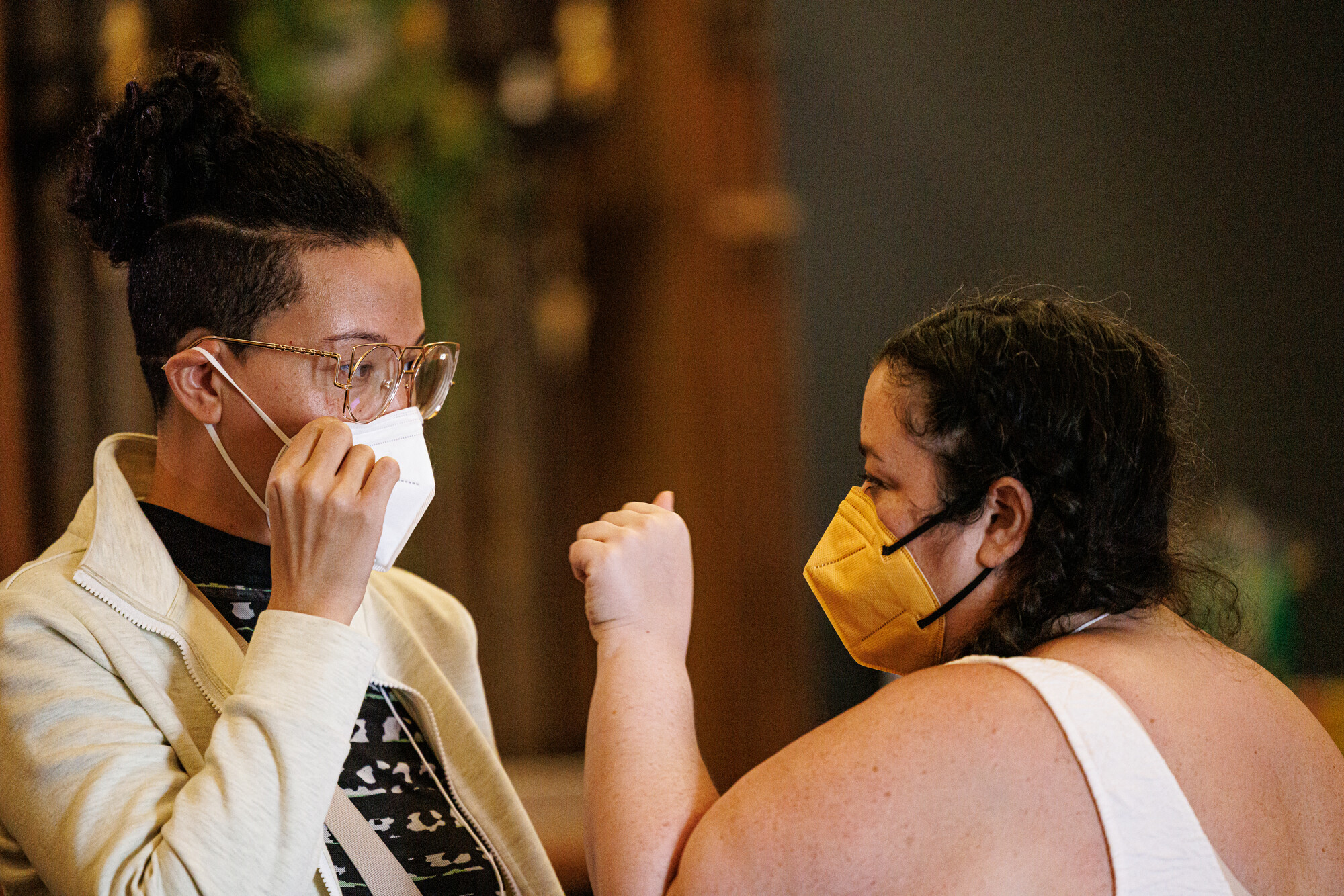 Two people in face masks looking at each other.