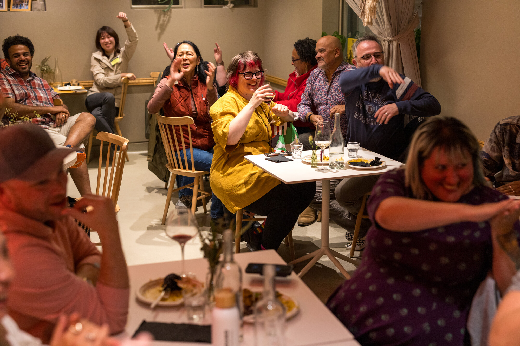 People sitting around at table and smiling and cheering.