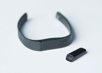 A black fitbit watch on a white surface.